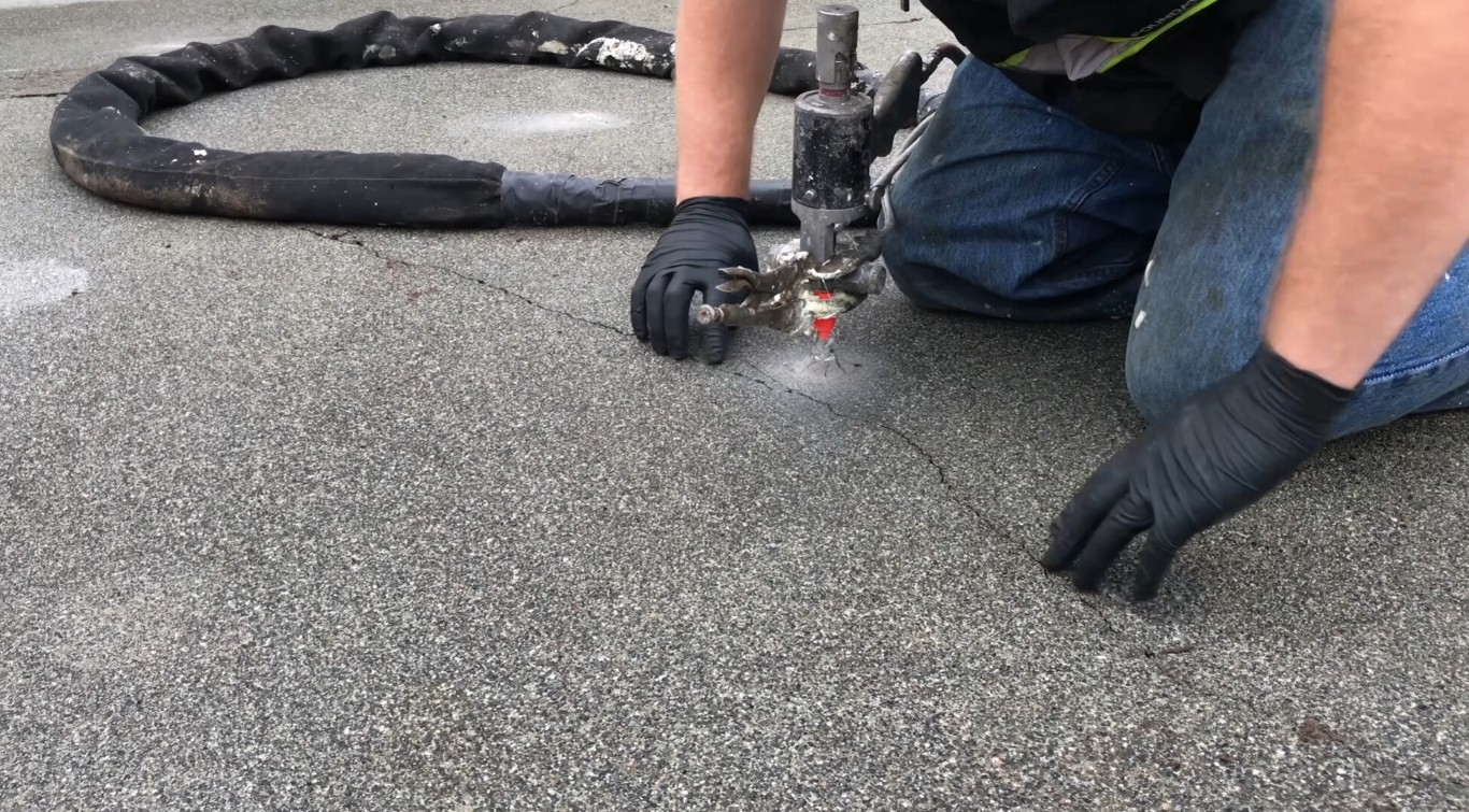 Technician repairing concrete crack with polyurethane injection tool
