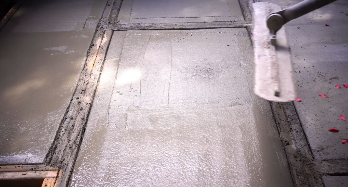 Concrete flatwork being finished with a bull float tool on a residential project